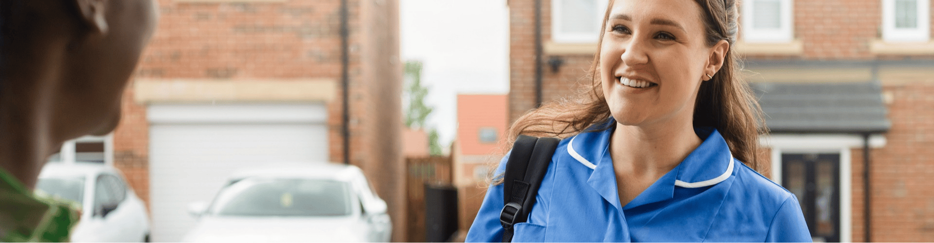 Woman smiling standing on a street in blue work clothes