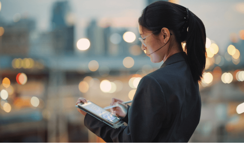 Person working on a tablet with city lights softly blurred behind