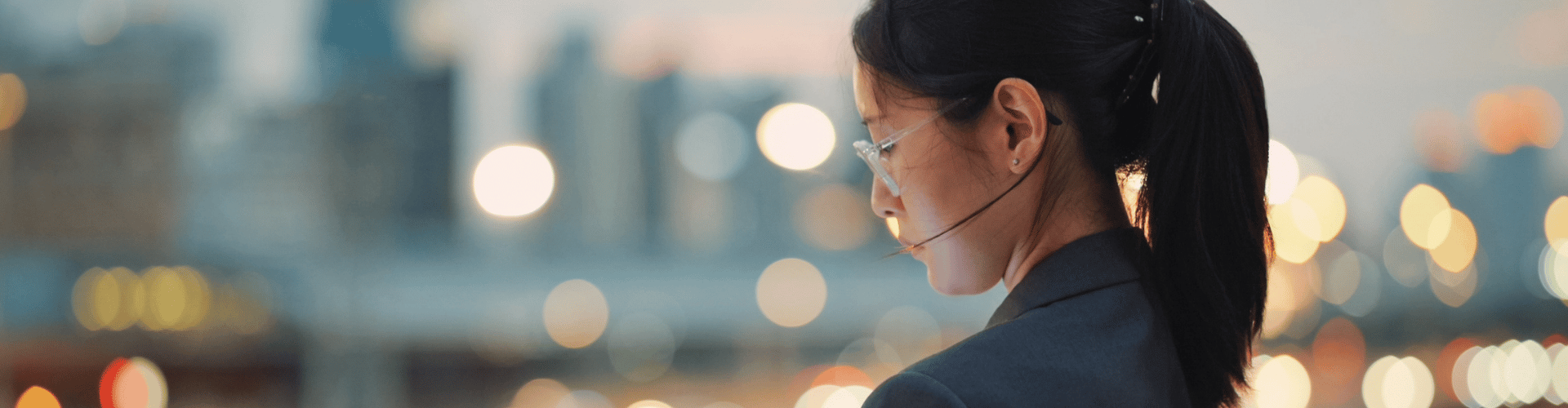 Person working on a tablet with city lights softly blurred behind