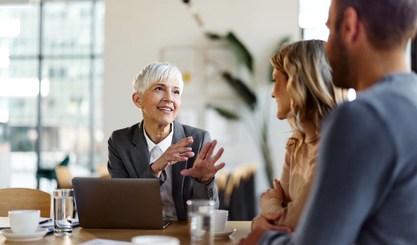 Business consultant speaking with two clients across a table during a meeting